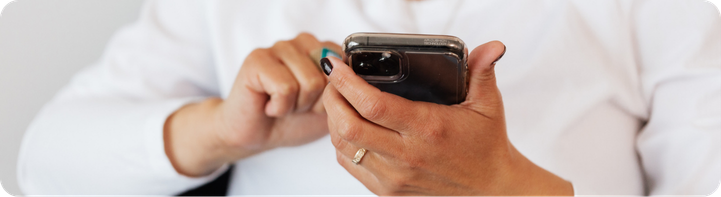 Dłonie osoby obsługującej smartfon.